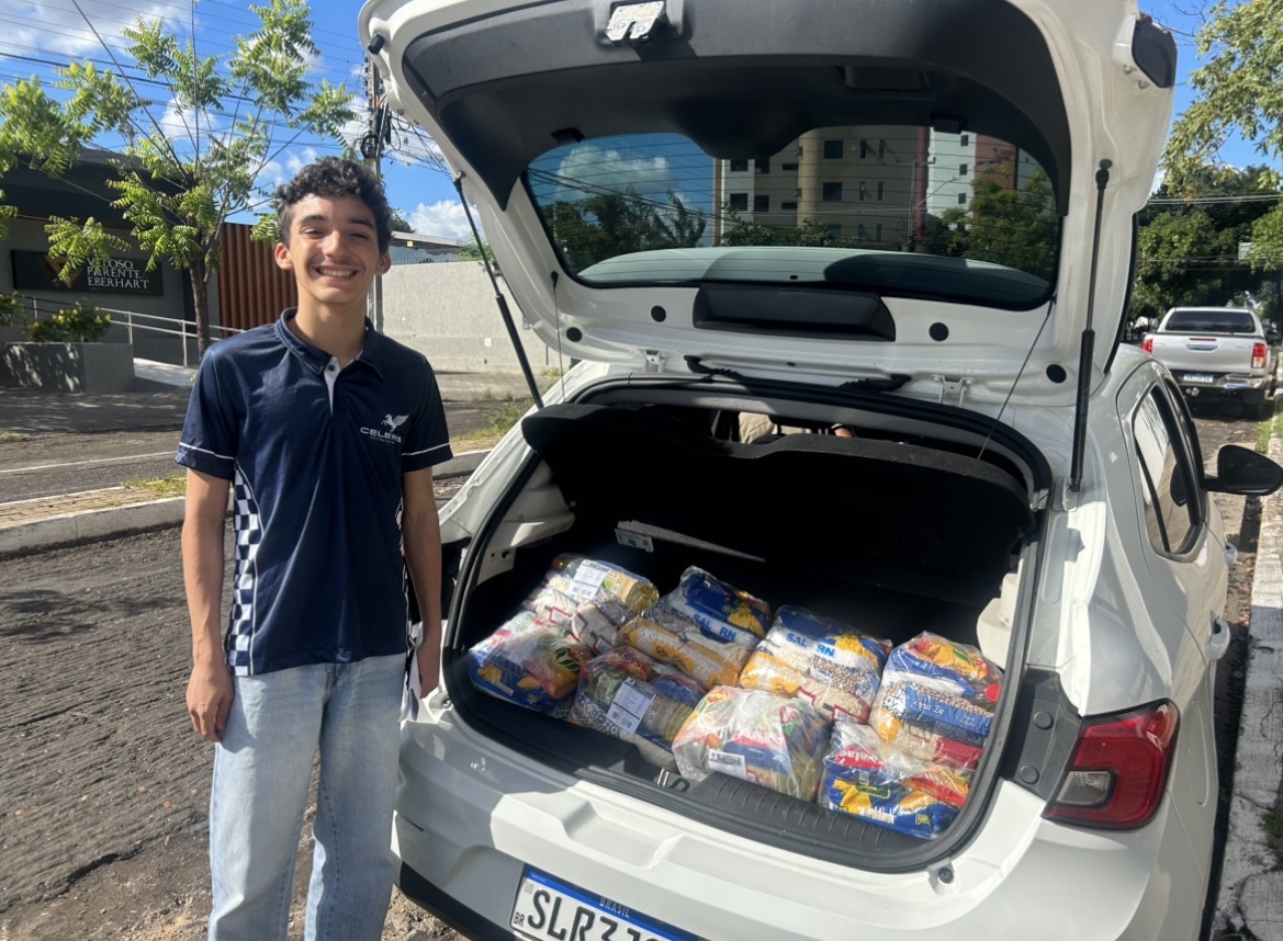 Aluno carregando as cestas básicas no porta-malas para entrega